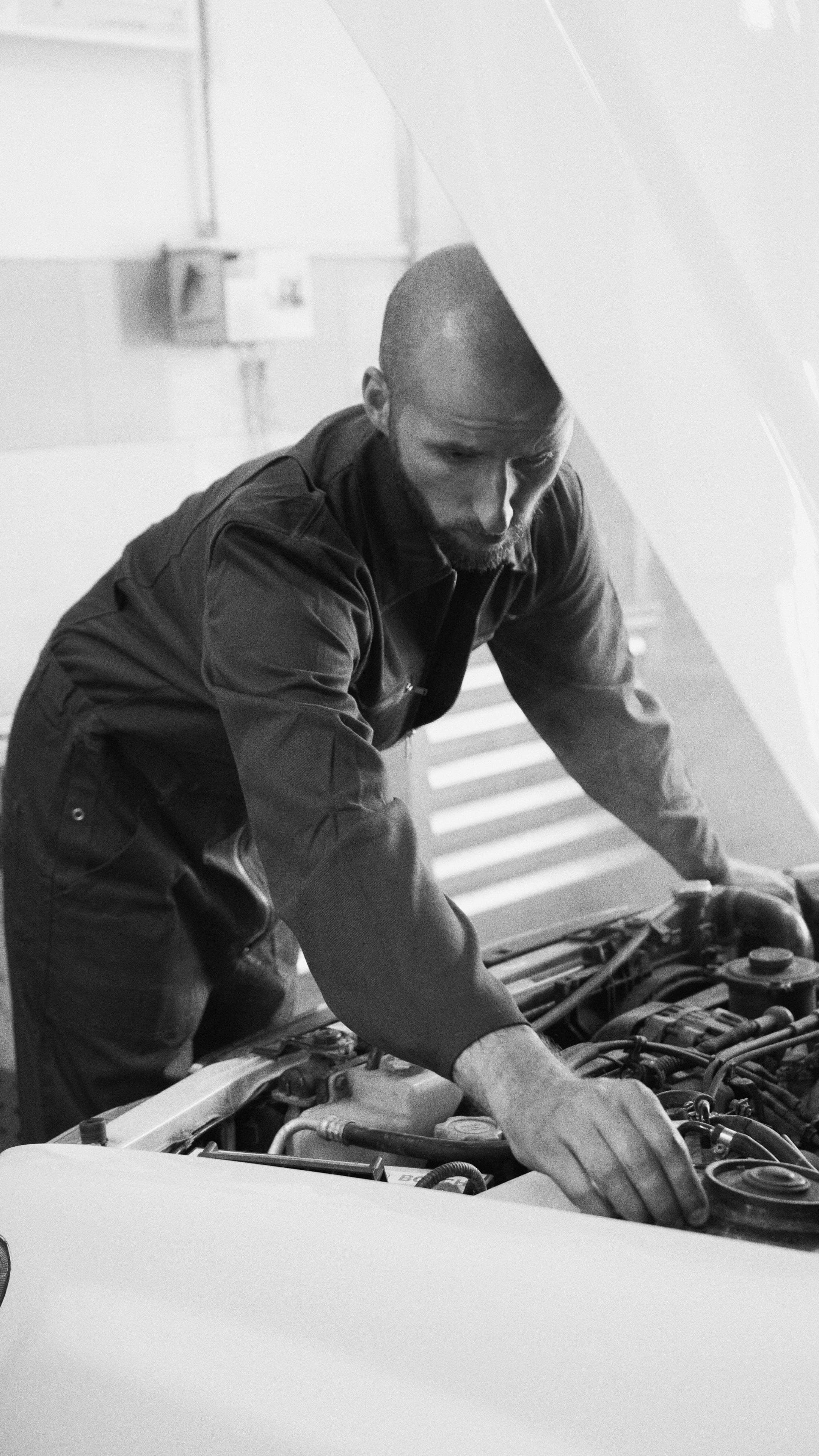 A mechanic leaning over an open engine bay